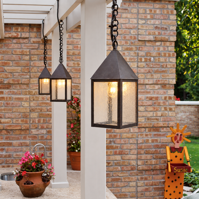 Two Carriage EX-5106-A18 solid brass chain hung outdoor pendant lights installed on a covered brick porch