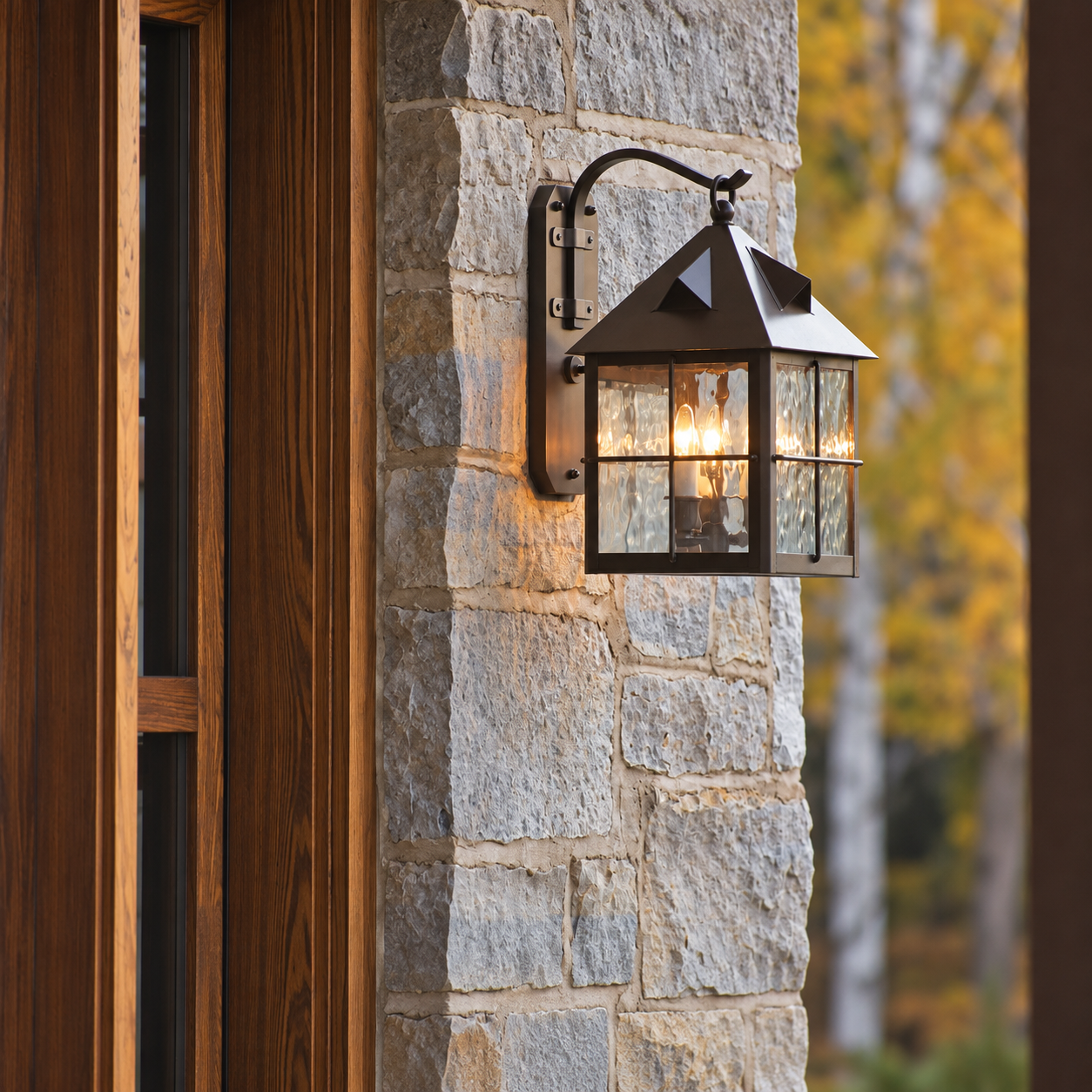 Stonehaven EX-6910-A42-WP solid brass outdoor wall lantern illuminated beside a stone home entrance